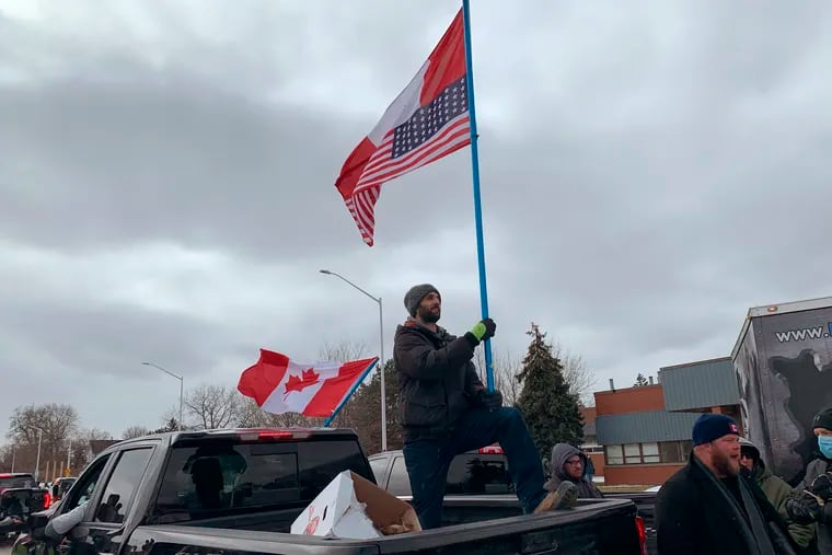 A protester waves Canada and U.S. flags in the backup of a pickup truck as police in Windsor, Ontario, moved protesters away from the entrance to the Ambassador Bridge, which has been blocked this week to Detroit, Saturday, Feb. 12, 2022. This week's demonstrations at the Ambassador Bridge, downtown Ottawa and elsewhere have targeted vaccine mandates and other coronavirus restrictions. There is also an outpouring of fury toward Prime Minister Justin Trudeau who has called them a “fringe” of Canadian society.