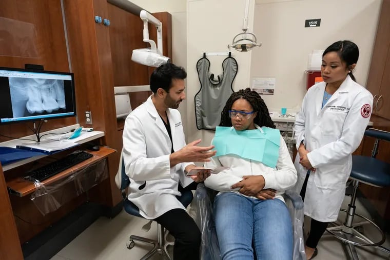 Adnan Kazim and Stephanie Serrano examine patient Dennita Cunningham, a contract writer for the department of the treasury, at Temple University's dental school on January 23, 2019.