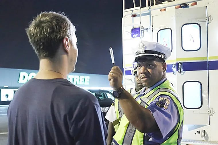 Police Officer Gary Harrison administers a sobriety test to a suspect during the DUI checkpoint at Aramingo and Butler run by the Accident Investigation Division in North Philly, Friday, July 19, 2013.