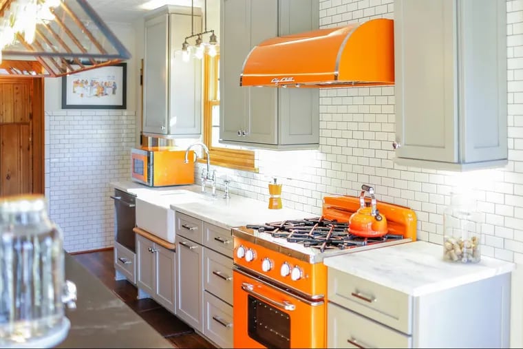 Color is coming back to kitchens. Here, bright orange Big Chill appliances — the microwave, stove and range hood — contrast more neutral cabinet.