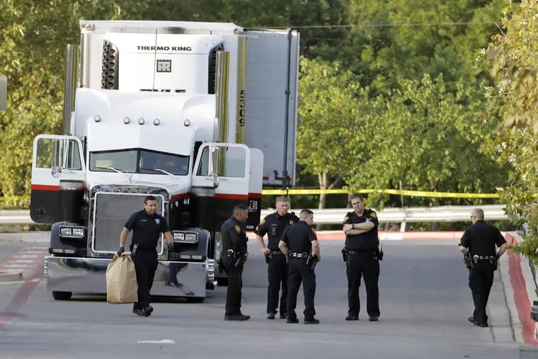 San Antonio police officers investigate the scene Sunday, July 23, 2017, where eight people were found dead in a tractor-trailer loaded with at least 30 others outside a Walmart store in stifling summer heat in what police are calling a horrific human trafficking case, in San Antonio.