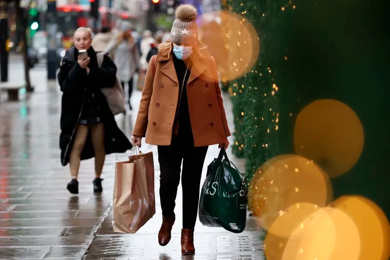 A woman wearing a face mask to guard against COVID-19 carries shopping bags along Oxford Street in London on Monday.