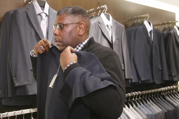 Ray Wertz checks out a sweater at Hugo Boss, where an average suit can cost $850 to $1,000. Many upscale stores, including Neiman Marcus and Nordstrom, have traded no-markdown policies for discounted prices in an effort to attract customers in a down economy. (Charles Fox / Staff Photographer)