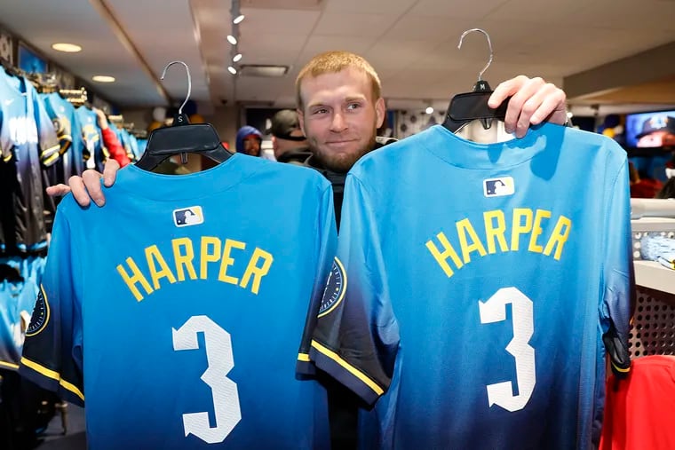 Justin Fullmer of Delaware County holds two Bryce Harper City Connect jerseys in the New Era Phillies Team Store at Citizens Bank Park on Friday.