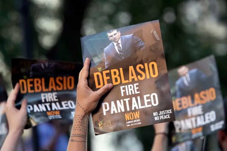 This Aug. 2, 2019 file photo shows demonstrators holding signs while calling on New York Mayor Bill de Blasio to fire police officer Daniel Pantaleo during a rally outside New York Police Department headquarters, in New York. Mayor Bill De Blasio's handling of the death of Eric Garner at the hands of Pantaleo and other officers in 2014 permanently poisoned his relationship with officers and also many of the activists who had helped elect him as a reformer. Both sides are now following around the country as he campaigns for the Democratic nomination for president.