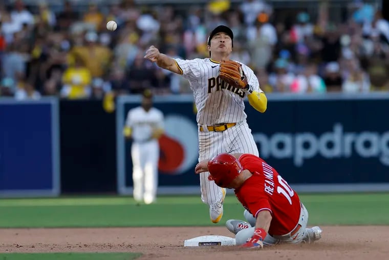 San Diego Padres shortstop Ha-Seong Kim turns a double play in the eighth inning as Phillies catcher J.T. Realmuto slides into second.