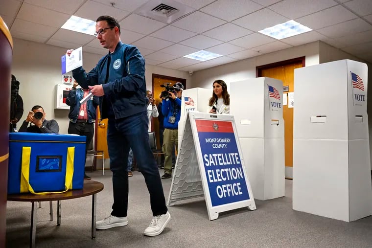 Pennsylvania Gov. Josh Shapiro shows his ballot to election officials before he drops it in the box, after casting his primary ballot early at a Montgomery County in-person satellite voting site in Willow Grove.