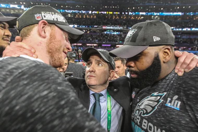 Eagles vice president Howie Roseman (center) hugs tackle Jason Peters (right) and quarterback Carson Wentz after they won Super Bowl LII.