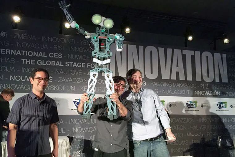 Andres Garza, project designer for the Meccanoid G15 KS, holds the 4-foot robot in triumph after it won the Last Gadget Standing competition at the Consumer Electronics Show. He was joined onstage by his brother and codesigner, Felipe Garza (left), and engineer Chris Hardouin. The Meccanoid, with 64 megabytes of memory and voice recognition, should be available by mid-August.