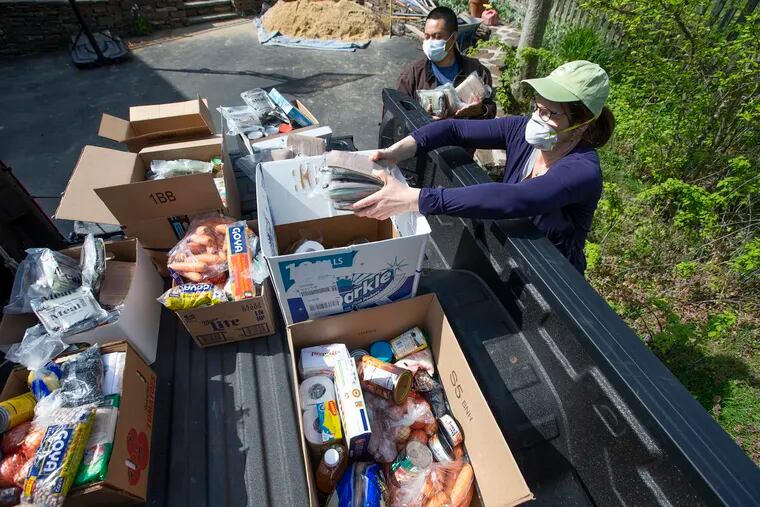 Layla de Luria (right) of Centro de Apoyo Comunitario in Upper Darby, and Antonio Escobar pack food-donation boxes for five needy families onto a truck in Wynnewood. The group is helping people who lost jobs due to the coronavirus pandemic.