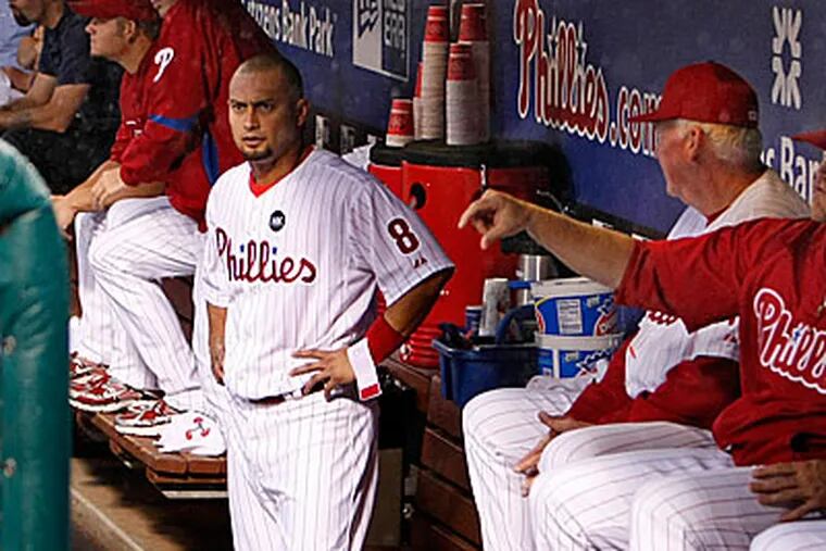 Shane Victorino watches from the dugout as the grounds crew covers the field during a rain delay in the first inning. (Ron Cortes/Staff Photographer)
