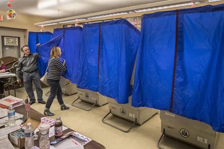 John Powell, left, the Judge of Elections for Ward 26, 4th Division, lifts the blue covering for a voter to enter the voting machine in the polling place at the bocci court at Marconi Plaza on Tuesday May 16, 2017.