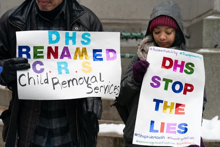 Harold Reed, left, and Jamie Lee Allen, right, hold signs to protest DHS outside of City Hall, in Philadelphia, February 12, 2019.