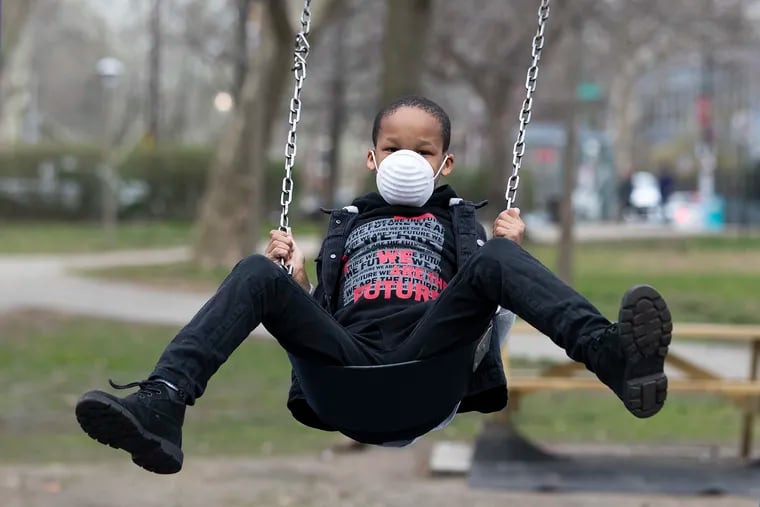 People were making use of Clark Park in West Philadelphia to escape the concerns of the virus and to get some exercise and fresh air on March 19, 2020.  Nafi Cannady, 8, wears a mask as he swings.  His mother, Trinia Cannady, said “The mask was for his safety and the safety of others.”  Her philosophy for her son is “to come out get some air and then go back inside.”