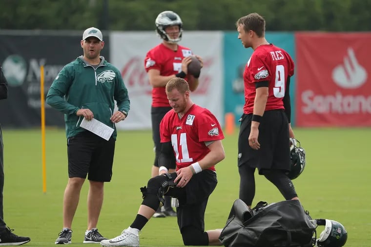 Carson Wentz, center, puts on his knee brace at Eagles training camp on Friday.
