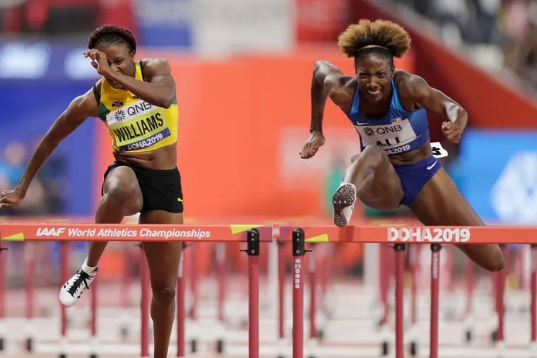 Nia Ali (right) clears a hurdle en route to winning the women's 100-meter hurdles final at the world championships in Doha, Qatar.