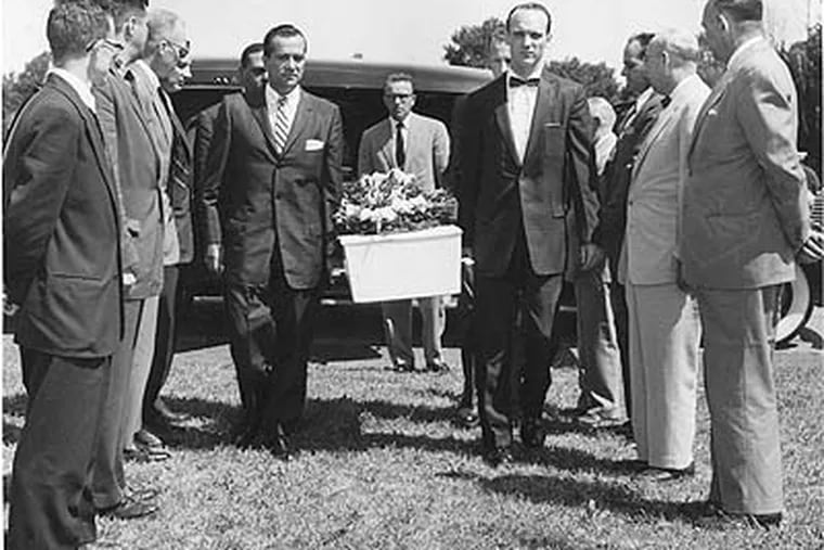 Detectives form an honor guard as the boy in the box is brought to the grave site in July 1957. Carrying the coffin are (left to right) Alan Ressa, Samuel Powell, Andrew Widger and Robert Gilton. Funeral director Henry S. Mann walks behind.