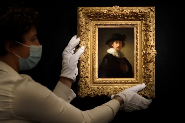 A Sotheby's employee adjusts a painting by Rembrandt, entitled 'Self-portrait, wearing a ruff and black hat' at Sotheby's auction rooms in London.
