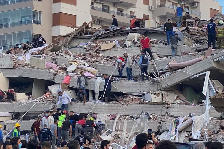 Rescue workers and local people try to save residents trapped in the debris of a collapsed building, in Izmir, Turkey, on Friday.