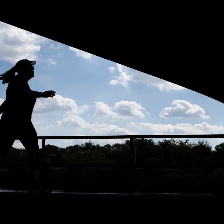 A runner moves along the Schyulkill River Trail under the Girard Avenue Bridge in Philadelphia on May 1, 2024.