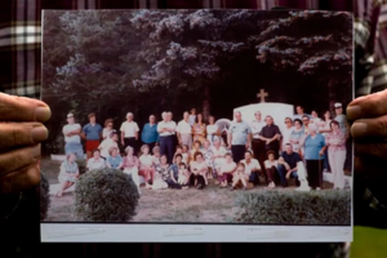 Mike Reilley Jr. holds a picture taken during a 1983 family gathering at the Byrnesville shrine. His father, Michael Reilley Sr., led the effort to build the shrine in the early 1950s.