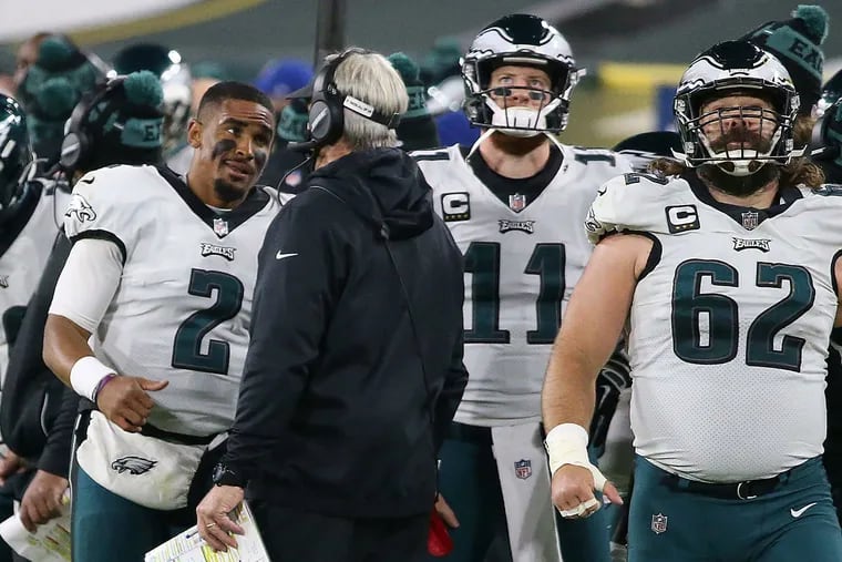 Eagles quarterback Jalen Hurts (2) talked with coach Doug Pederson (center) after he replaced Carson Wentz (11) in the third quarter against the Green Bay Packers in Week 13.