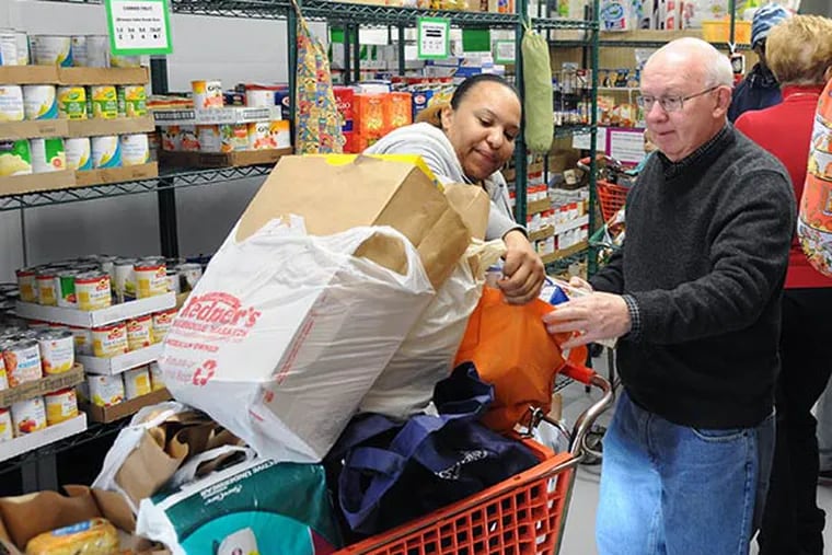 Larry Hannigan, 69, Eagleview, helps Cynthia Washington, 27, of West Chester, pick out groceries for her and her five children on Dec. 12, 2013. The pantry registered its biggest day ever in late November, the first month of the nationwide cuts to food stamps. (CLEM MURRAY / Staff Photographer)