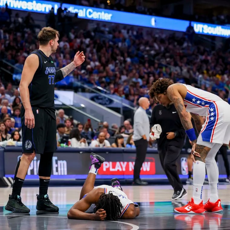 Sixers guard Tyrese Maxey holds his head  as Dallas Mavericks guard Luka Doncic (left) and Kelly Oubre Jr. look on Sunday. Maxey returned to the game later.
