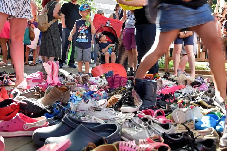 Ethan Schiller (left), 4, and his brother Lukas Schiller (right), 2-1/2, look over the dozens of shoes representing children who were separated from their parents by immigration officials, during a protest outside the Rittenhouse Hotel June 19, 2018 where Vice President Pence attended a fundraiser for GOP gubernatorial nominee Scott Wagner.