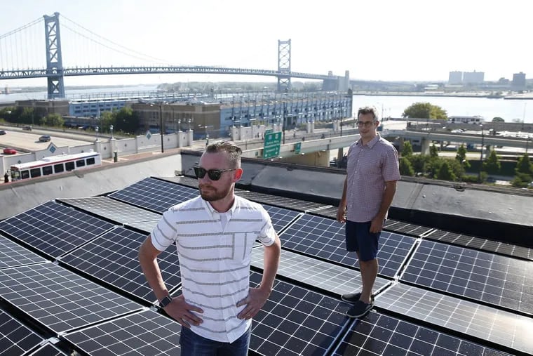 Micah Gold-Markel, right, owner Philadelphia  installation company Solar States, says that new solar import tariffs  will make solar investment less attractive. He is shown here in 2016 with Darren Hill, who hired Solar States to install panels on an Old City building.