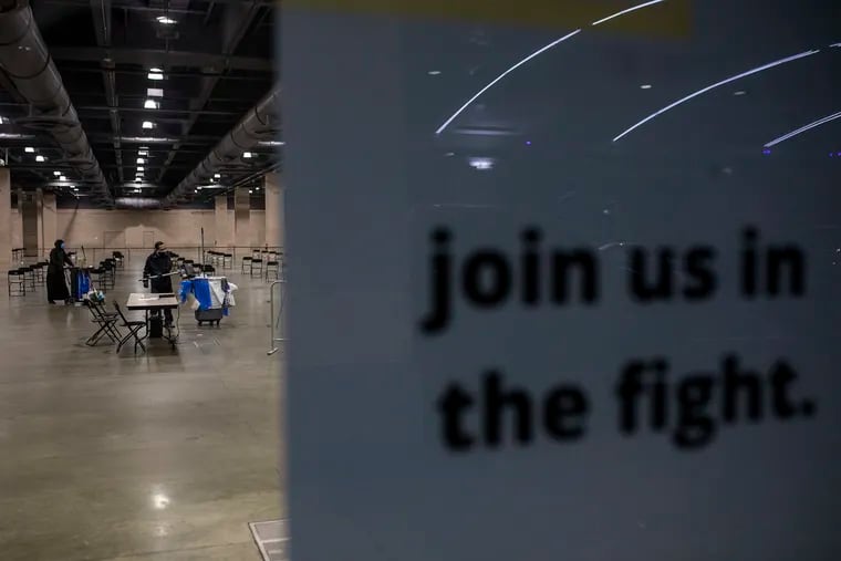 Workers clean up trash in the empty Philly Fighting COVID clinic at the Pennsylvania Convention Center late last month.