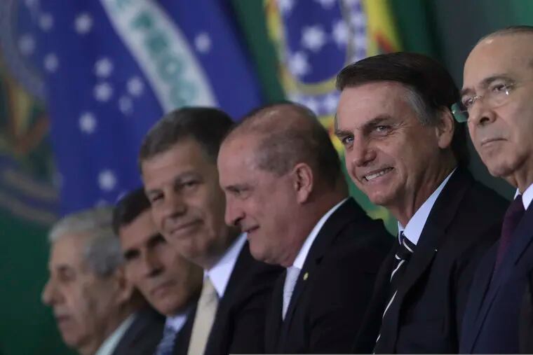 Brazil's President Jair Bolsonaro smiles amid members of his cabinet as he presents them during a ceremony at the presidential palace in Brasilia, Brazil, Wednesday, Jan. 2, 2019. (AP Photo/Eraldo Peres)