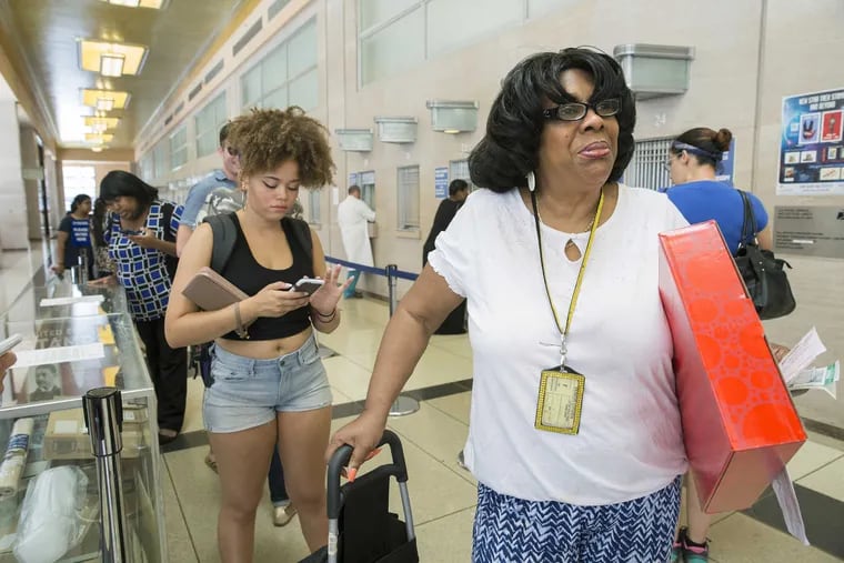 Customers Chloe Brown (back left) and Joan Luby (front right) wait in a short line at the William Penn Annex post office branch at Ninth and Market Streets in Philadelphia.