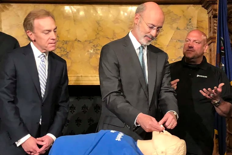 Gov. Tom Wolf, center, listens as Elvis Rosado, right, of Philadelphia-based Prevention Point advises him how to administer a nasal spray that reverses an opioid overdose during a demonstration in Wolf's Capitol offices, Wednesday, May 22, 2019, in Harrisburg, Pa. Looking on is Paul Tufano, CEO of AmeriHealth Caritas, a Medicaid insurer that sponsors training. (AP Photo/Marc Levy)