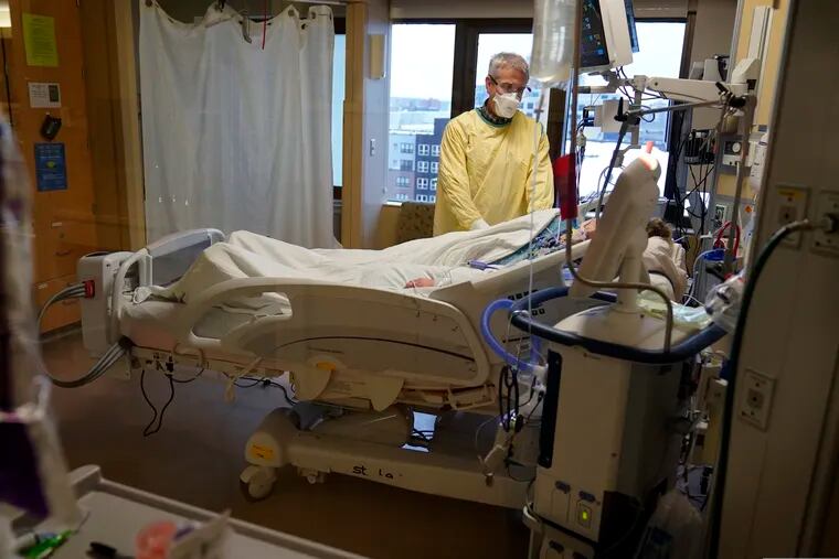Steve Grove, a chaplain at Hennepin County Medical Center, prays in a COVID-19 patient's room in December.