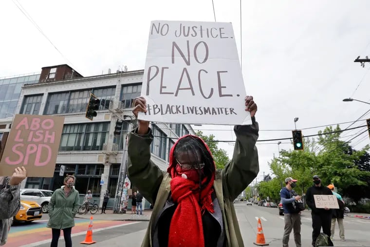 Demonstrator Kathy Woodward holds up a sign as she protests police actions, Thursday, June 4, 2020, in Seattle, following protests over the death of George Floyd. An armed driver on Sunday barreled toward a crowd of protester, shooting one.