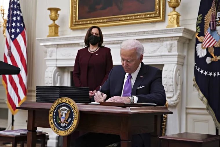 President Joe Biden signs an executive order after speaking during an event on his administration's COVID-19 response with Vice President Kamala Harris in the State Dining Room of the White House on Thursday.