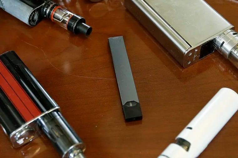 FILE – This Tuesday, April 10, 2018 file photo shows vaping devices, including a Juul, center, that were confiscated from students at a high school in Marshfield, Mass.