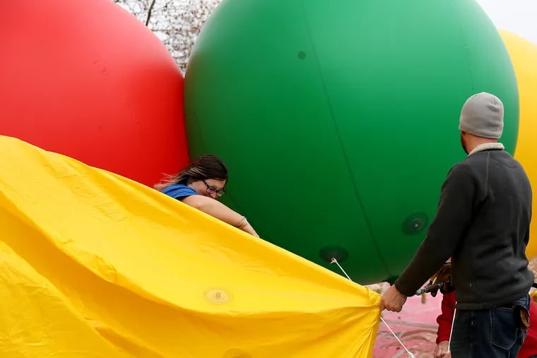 Theresa Yeager, left, and Cliff Booher, right, of Star Bound Entertainment, battle the wind as they inflate production spheres as preparations continue around the Ben Franklin Parkway for the 6ABC Dunkin’ 100th Thanksgiving Day Parage in Philadelphia, PA on November 27, 2019. Strong wind gusts are predicted for Thursday.