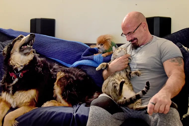 Brent Adams with some of his seven animals (not counting his fish) at his home in Grays Ferry. He is holding Buster, 11. Seated with him are Jasmine, 7 (left), a Rottweiler-Husky mix; and Polo, 7 (center), a Pomeranian.