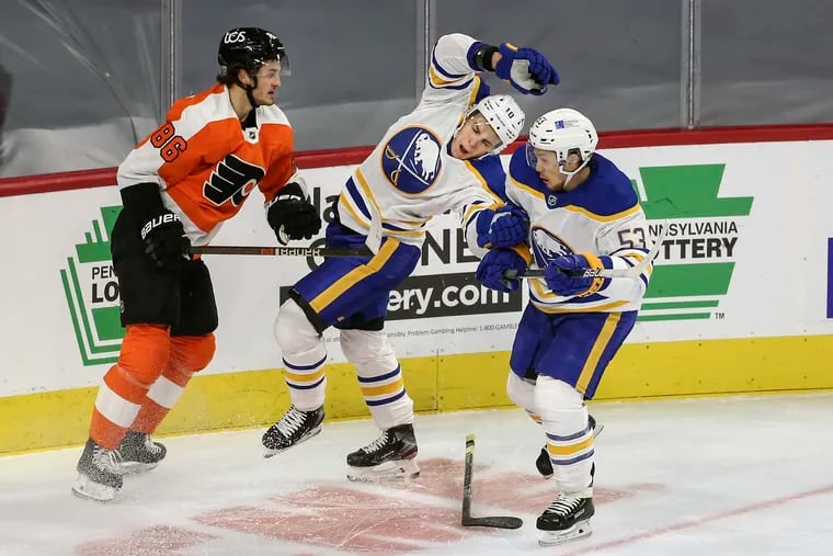 Flyers winger Joel Farabee (left) checks the Sabres' Henri Jokiharju as Jeff Skinner (53) looks on during Tuesday night's game. The Flyers won, 3-0, and outhit the Sabres, 37-18.