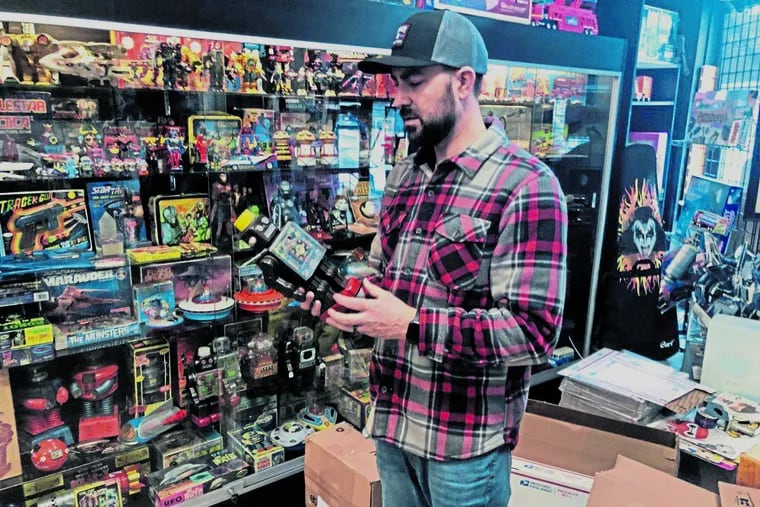Jermy Fairgrieve, owner of Pop Culture Connections in Greensburg, packs a Buck Rogers Atomic Pistol toy made in the 1930s.