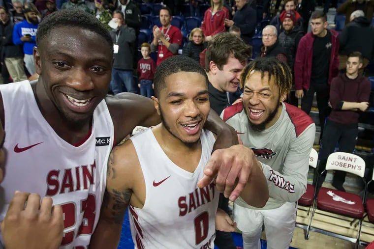 Fresh Kimble, center, celebrates with his St. Joseph's teammates, Markell Lodge, left, and Troy Holston, right.  Kimble hit a 3-pointer to give St. Joseph's a 45-42 victory over Loyola Chicago on Dec. 22, 2018, at the Palestra.  CHARLES FOX / Staff Photographer