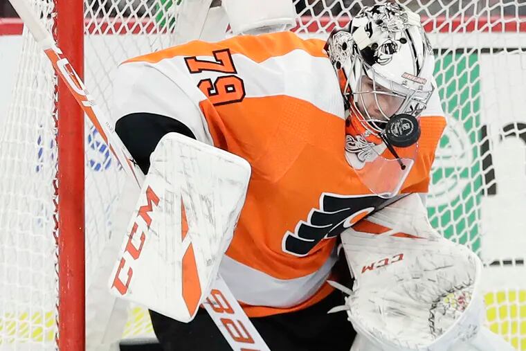 Flyers goaltender Carter Hart takes the puck off his mask.