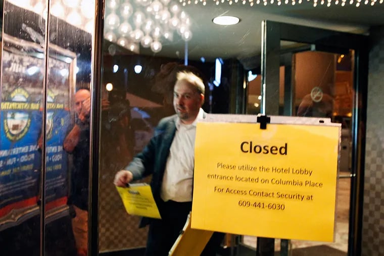 At 6 a.m. Tuesday, Trump Plaza employee Bill Norwood places closed signs on the Boardwalk of the Trump Plaza casino.