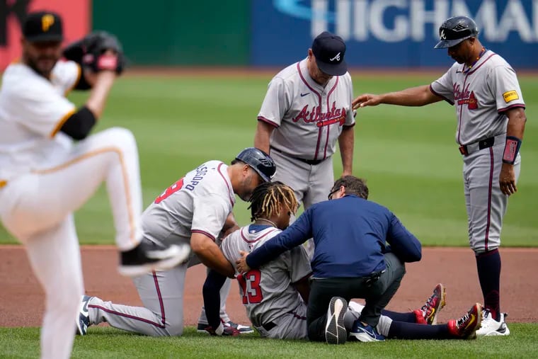 Atlanta Braves outfielder Ronald Acuña Jr. is tended to after he hurt his left knee running the bases against the Pittsburgh Pirates on Sunday.