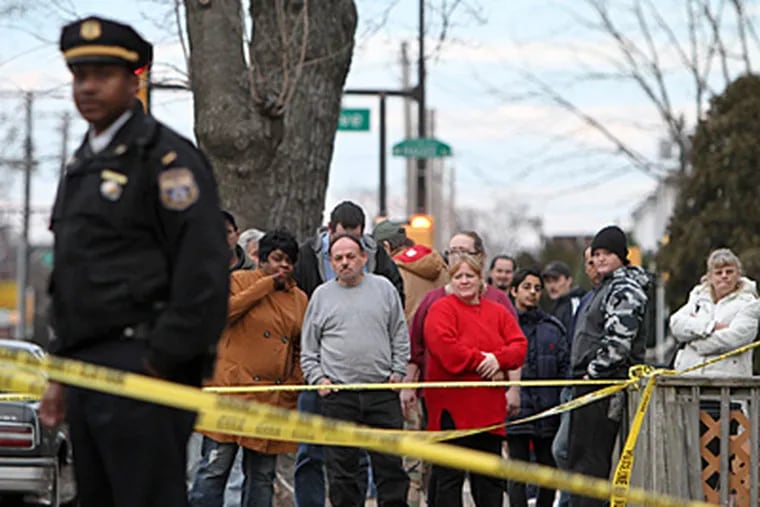 Neighbors watch as police investigate a homicide along the 6500 block of Torresdale Ave, on Tuesday in northeast Philadelphia. Police believe a man shot and killed another neighbor after an argument over dog droppings. (For the Daily News/ Joseph Kaczmarek)