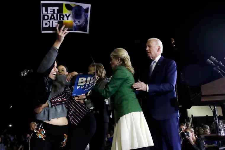 A protester at left, is held back by Biden adviser Symone Sanders, wearing stripes, face unseen, and Jill Biden, second from right, as Democratic presidential candidate former Vice President Joe Biden stands, at right, during a primary election night rally, Tuesday, March 3, 2020, in Los Angeles.