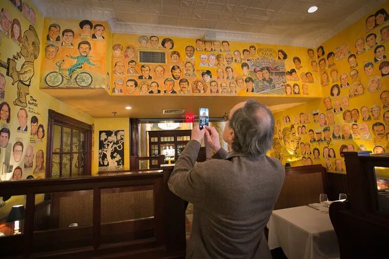 Maury Z. Levy takes a picture of his portrait on the wall at the Palm.