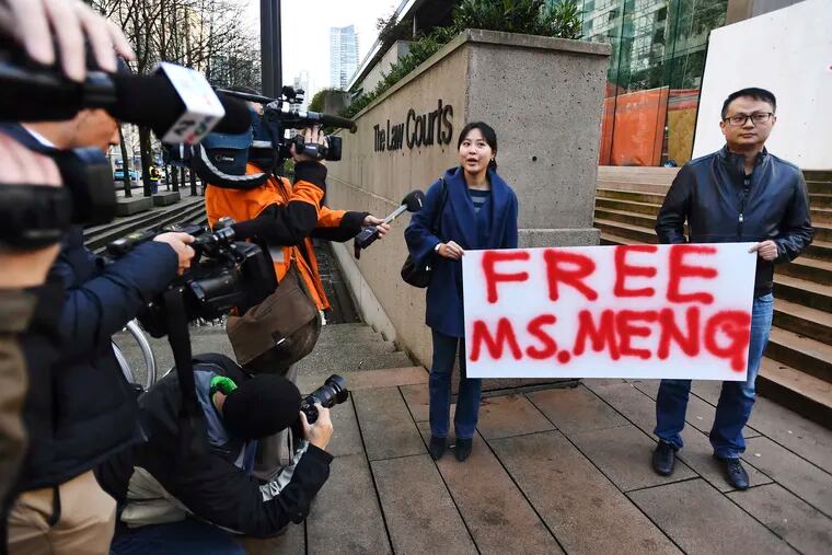 People hold a sign at a Vancouver, British Columbia courthouse prior to the bail hearing for Meng Wanzhou, Huawei's chief financial officer on Monday, December 10, 2018. Meng Wanzhou was detained at the request of the U.S. during a layover at the Vancouver airport on Dec. 1.(Jonathan Hayward/The Canadian Press via AP)
